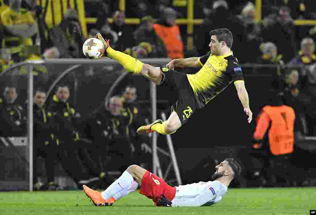 Dortmund's Sokratis, up, and Salzburg's Munas Dabbur, on the ground, challenge for the ball during the Europa League soccer match between Borussia Dortmund and FC Salzburg in Dortmund, Germany.