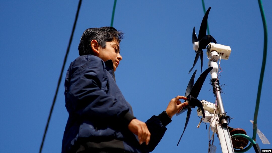Displaced Palestinian teenager Hussam Al-Attar works on wind turbines, that he uses to light up his shelter during power cut, at a tent camp in Rafah, in the southern Gaza Strip, February 6, 2024. (REUTERS/Ibraheem Abu Mustafa)