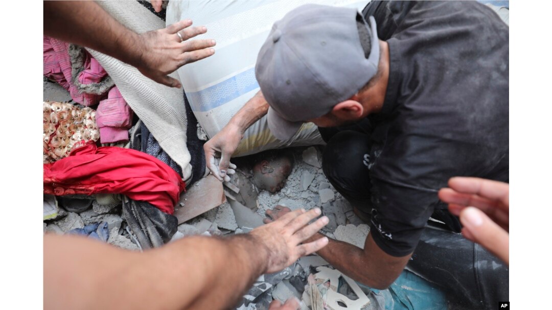 Palestinians try to pull out a child after the Israeli bombardment of the Gaza Strip in the Nusseirat refugee camp, Oct. 24, 2023.