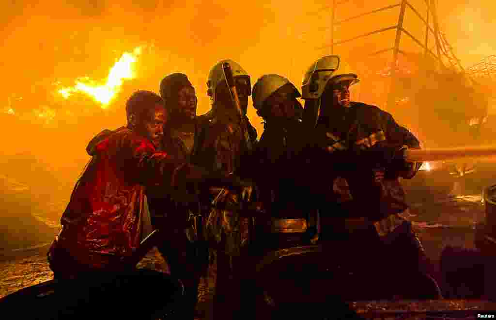 Firefighters and volunteers attempt to extinguish a fire that broke out at a commercial depot, used for oil barrels and flammable drums, near Muthurwa settlement, in Nairobi, Kenya, Jan. 30, 2024.