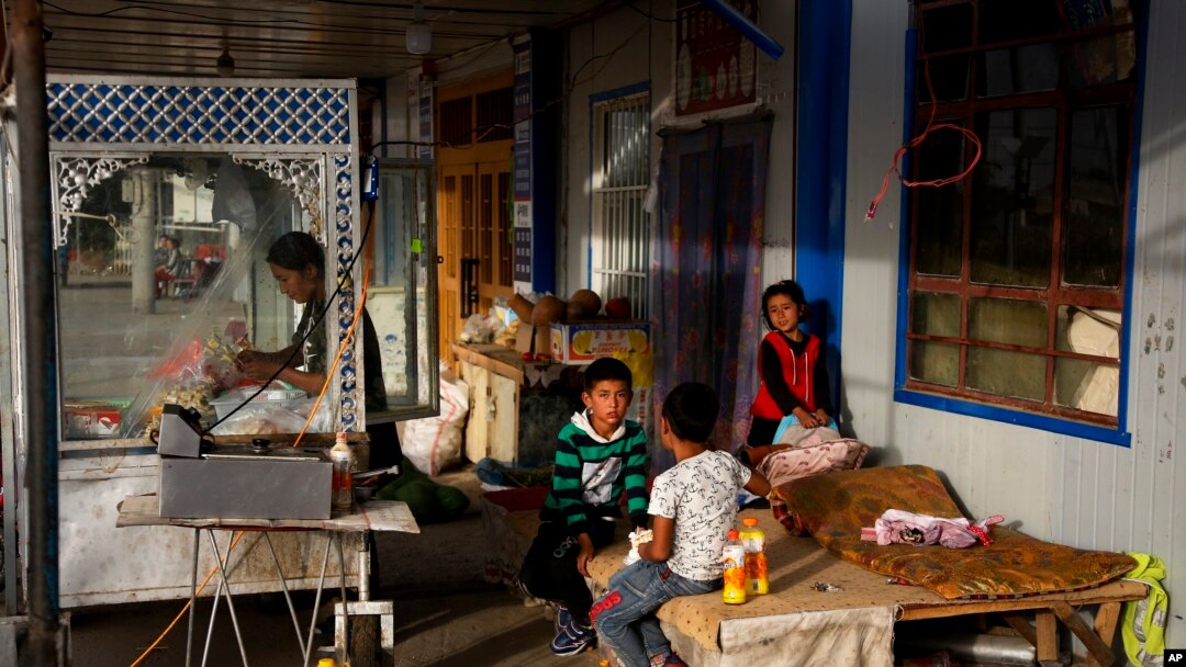 FILE - A Uyghur woman works while children play in Hotan, in western China's Xinjiang region, Sept 20, 2018. China faced international criticism about its human rights record, mainly on its treatment of Uyghurs, Thursday at a United Nations Human Rights Council session in Geneva.