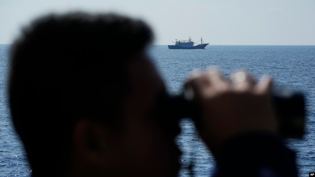 FILE - A suspected Chinese militia ship passes as the Philippine Coast Guard BRP Malabrigo drives it away from Philippine-occupied areas in the South China Sea on April 21, 2023.