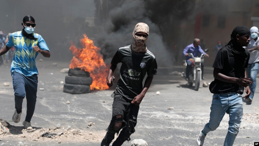 FILE — Protesters run for cover from tear gas fired by police during a protest against insecurity in Port-au-Prince, Haiti, Aug. 7, 2023. 