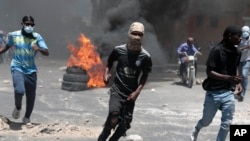Protesters run for cover from tear gas fired by police during a protest against insecurity in Port-au-Prince, Haiti, Aug. 7, 2023. 