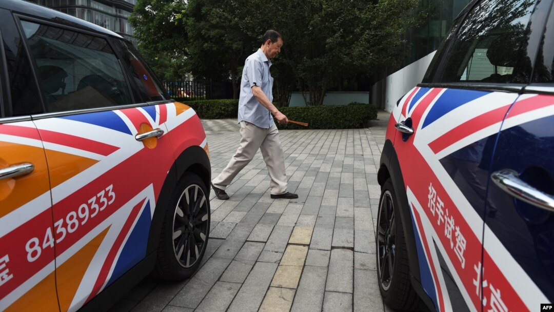 FILE - A man walks past Mini cars decorated with the British flag, outside a showroom in Beijing, China, June 27, 2016.