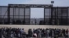 FILE - Migrants wait at the U.S.-Mexico border as U.S. Border Patrol agents stand guard, seen from Ciudad Juarez, Mexico, March 30, 2023. 