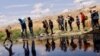 Migrants seeking asylum cross the Rio Bravo river to return to Mexico from the United States, after members of the Texas Army National Guard extend razor wire to inhibit migrants from crossing, as seen from Ciudad Juarez, Mexico, May 13, 2023. 