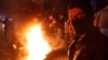 An anti-government protester stands next to burning tire during ongoing protests against the country's financial woes, in Beirut, Lebanon, Jan. 15, 2020.