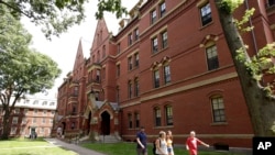Des gens marchent le long d'un trottoir sur le campus de l'Université Harvard, à Cambridge, Mass., le 16 juillet 2019.