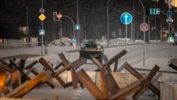乌克兰首都基辅，乌克兰武装部队的一辆装甲车在路障后面的道路上行驶。（2022年3月19日）