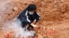 A woman takes part in a Buddhist ceremony in honor of the victims in a field close to the site where a China Eastern Airlines Boeing 737-800 plane crashed, in Wuzhou, Guangxi Zhuang Autonomous Region, China, March 22, 2022. 