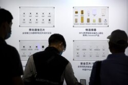 FILE - People look at semiconductors made by Tsinghua Unigroup on display at the China Beijing International High Tech Expo in Beijing, Sept. 19, 2020.