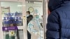 2022年12月15日，一名男子在北京一家医院的发热门诊门外排队等待。一位身着防护服的医务人员正准备关门。中国有关当局毫无预兆地宣布解封后，新冠肺炎的感染人数和死亡人数不断增加，引起人们的恐慌。