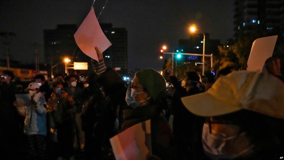 Protesters hold up blank papers and chant slogans as they gather on a street during a protest in Beijing, Nov. 27, 2022.