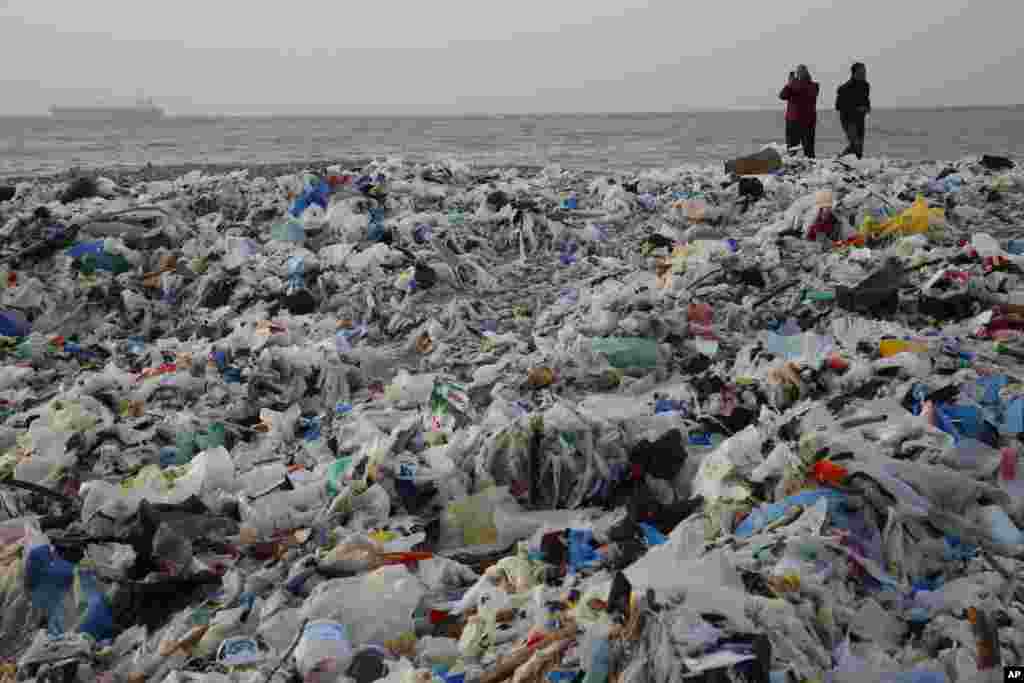 A man takes photos of piles of garbage washed ashore after a storm battered the Mediterranean country at the Zouq Mosbeh costal town, north of Beirut, Lebanon, Jan. 22, 2018.