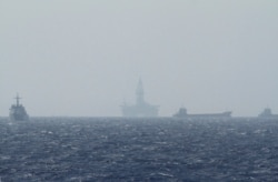 FILE - Ships and an oil rig, center, which China calls Haiyang Shiyou 981, and Vietnam refers to as Hai Duong 981, is seen in the South China Sea, off the shore of Vietnam, May 14, 2014.