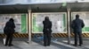 FILE - A man, center, reads the Chinese state-run newspaper with coverage of the conflict between Russia and Ukraine, on a street in Beijing, Feb. 24, 2022.