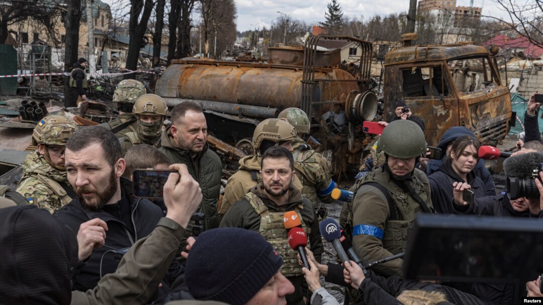Ukraine's President Volodymyr Zelenskiy speaks to the media as he is surrounded by Ukrainian servicemen in Bucha, outside Kyiv, April 4, 2022.