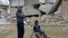 Mahmoud Madarati, 55, poses as he stands near his son whose leg and hand were amputated after sustaining injuries by what Mahmoud says was shelling from government-held areas, northern Syria, March 3, 2022. 