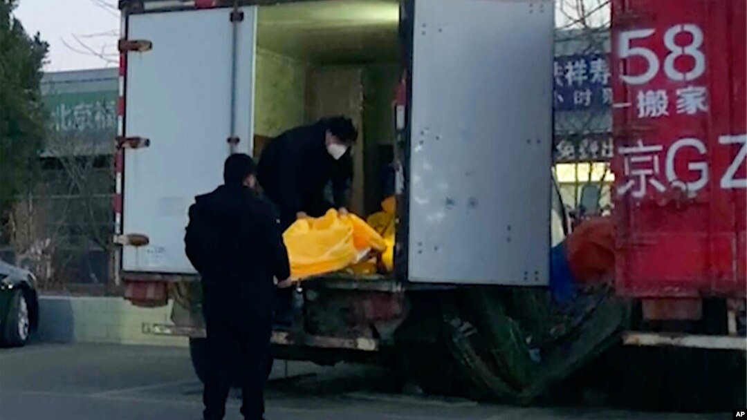 Workers load body bags into a truck at a funeral complex in Beijing, Dec. 16, 2022.
