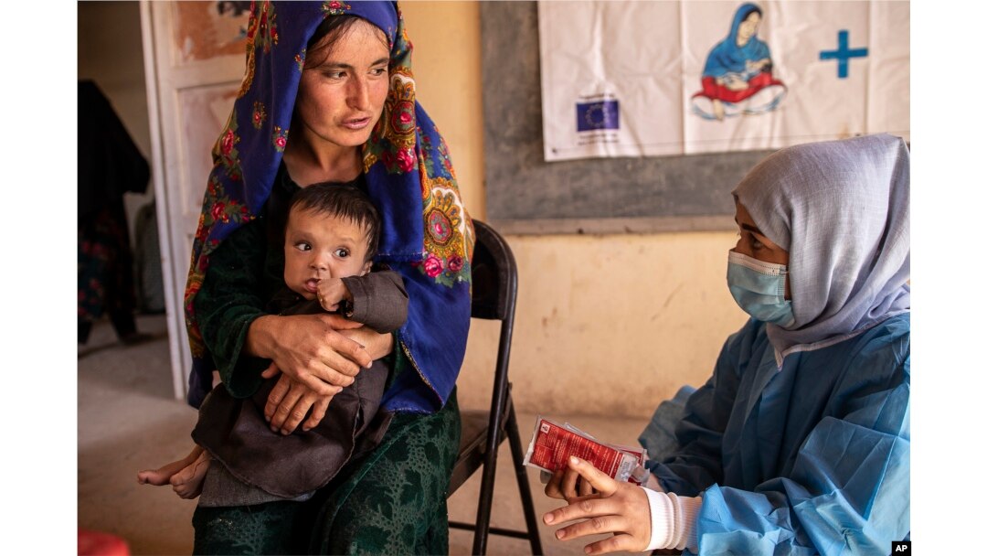 FILE - A Save the Children nutrition counselor, right, explains to Nelab how to feed her 11-month-old daughter, Parsto, with special food, in Sar-e-Pul province of Afghanistan, Thursday, Sept. 29, 2022. (Save the Children via AP, File)