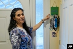 Koloud Kej Tarapolsi pokazuje na držač za maske koji je napravila njena ćerka i na kome je na arapskom napisana fraza "Za vaše zdravlje", u njenom domu u Redmondu, u državi Vašington. (Foto: AP/Ted S. Warren)