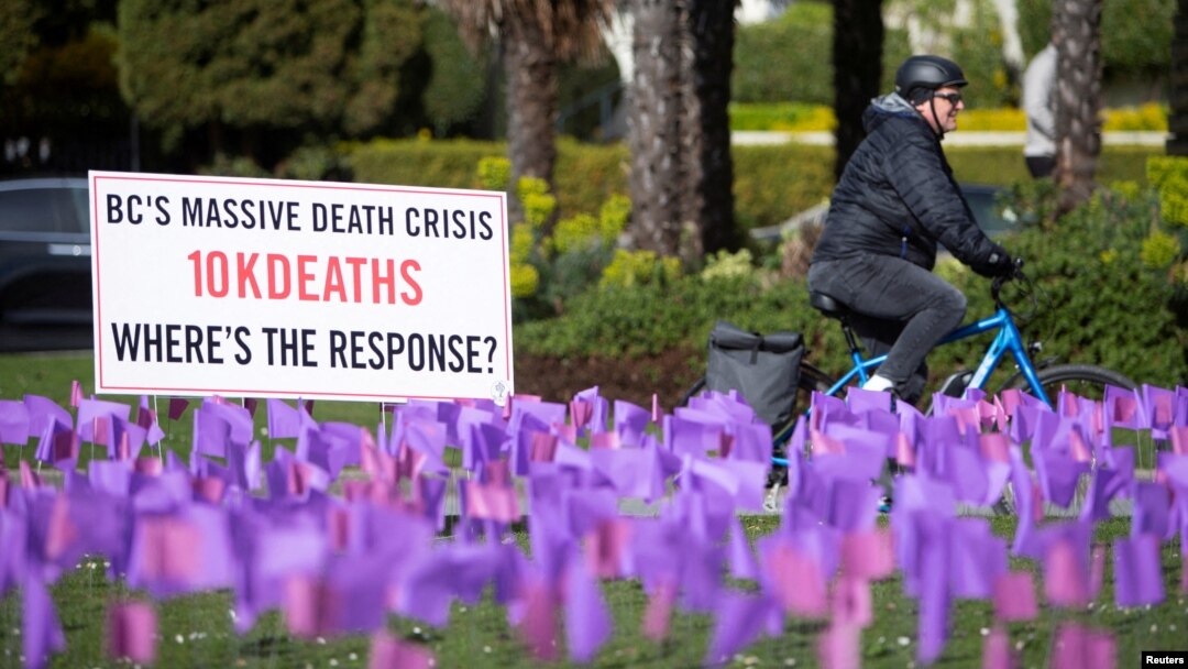 FILE - A cyclist rides past flags symbolizing the more than 10,000 people who have died of toxic drug overdoses in British Columbia, Canada, during a demonstration by the drug user advocacy group Moms Stop The Harm in Vancouver, British Columbia, Canada, on April 14, 2022.