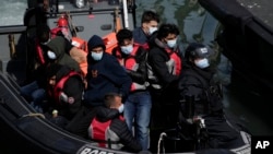 FILE - People thought to be migrants who undertook the crossing from France in small boats and were picked up in the Channel, arrive to be disembarked from a small transfer boat which ferried them from a British border force vessel, in Dover, south east England, June 17, 2022.