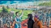 FILE - A couple wearing face masks walk past a painting to mark the country's Youth Day holiday in Soweto, South Africa, June 16, 2020. 