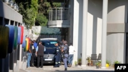 FILE - In this file photo taken on Feb. 14, 2018 a police van and uniformed and plainclothes police officers are seen inside the compound of the controversial business family Gupta in Johannesburg. 