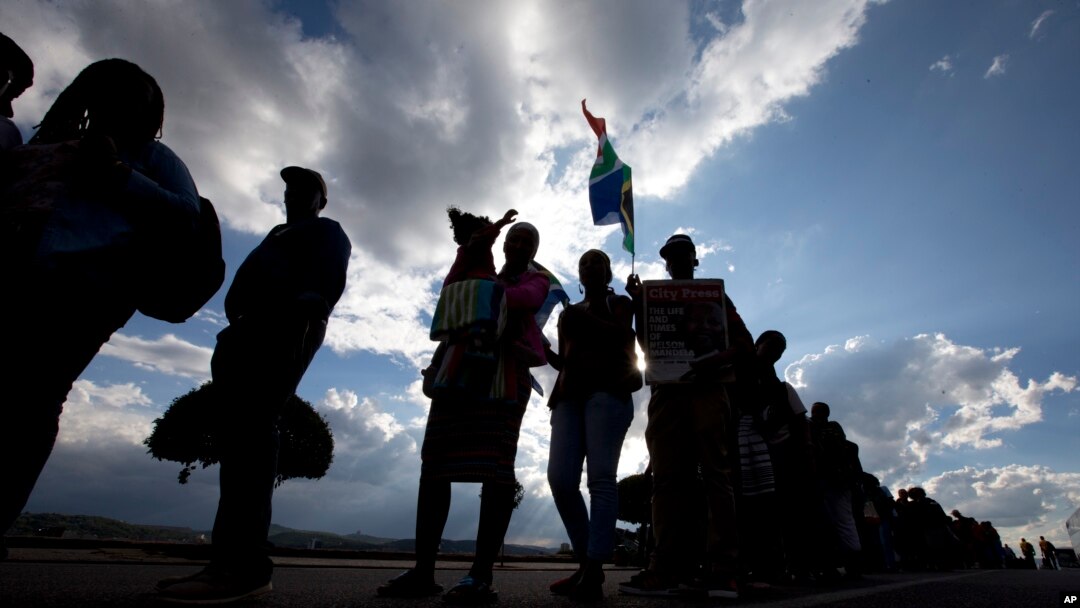 People are silhouetted against a late afternoon sun as they queue to see the remains of Nelson Mandela at the Union Buildings in Pretoria, South Africa, Dec. 11, 2013, where his body lies in state for three days.
