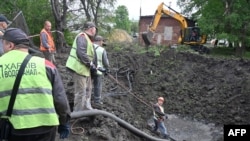 Працівники комунальних служб працюють біля вирви у дворі лікарні в Харкові після російського масованого ракетного удару по Україні, що пошкодив чотири електростанції. 27 квітня 2024 року.