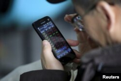 FILE - An investor checks stock information on a mobile phone at a brokerage house in Shanghai, China, March 7, 2016.