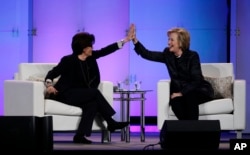 FILE - Hillary Rodham Clinton, right, and technology commentator Kara Swisher high-five during a keynote address at the Watermark Silicon Valley Conference for Women.