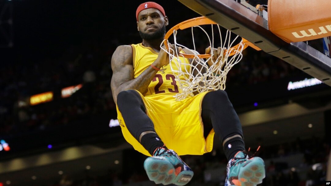 Cleveland Cavaliers forward LeBron James (23) hangs onto the basket after a dunk during the second half of an NBA basketball game against the Miami Heat in Miami, Dec. 25, 2014. James was called for a technical foul on the play.