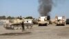 Smoke is seen rising from the Brigade Qaqaa headquarters, a former Libyan Army camp known as Camp 7 April, behind members of the Libya Shield, following clashes between rival militias at the Sawani road district in Tripoli, Aug. 24, 2014. 