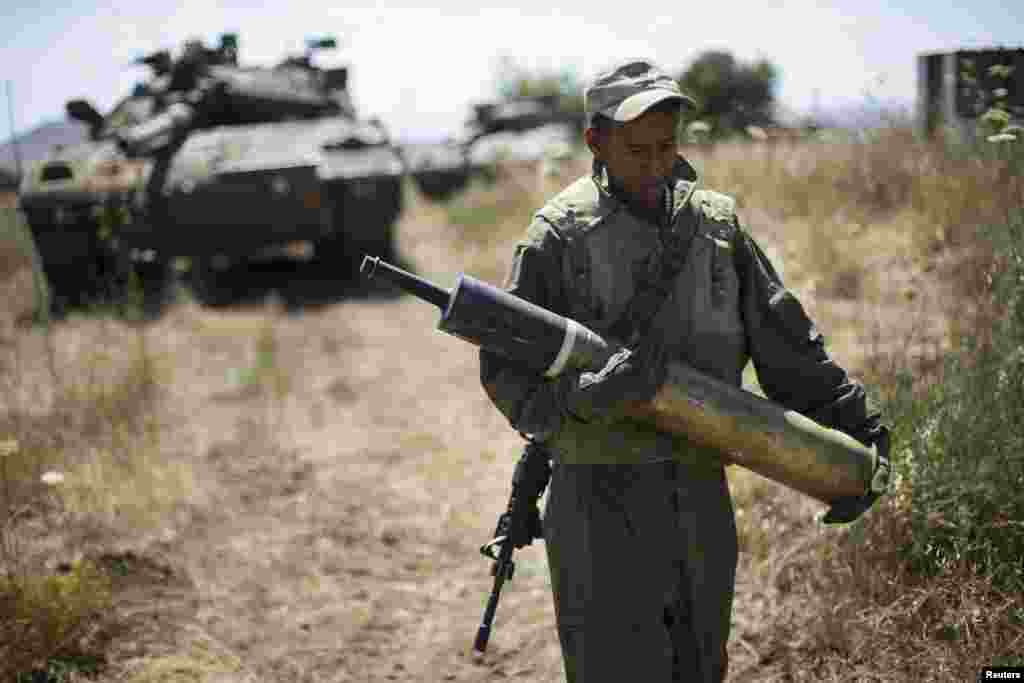 An Israeli soldier carries a tank shell near Alonei Habashan on the Israeli occupied Golan Heights, close to the ceasefire line between Israel and Syria June 22, 2014.