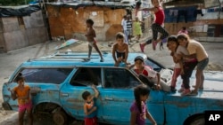 Children play on top of an abandoned car at the "Aguerridos Liberator" shanty town in Caracas, Venezuela, May 9, 2019. 
