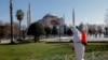 FILE - A worker in a protective suit disinfects Sultanahmet square, with Hagia Sophia in the background, in response to the spread of coronavirus disease (COVID-19) in Istanbul,Turkey, March 21, 2020.