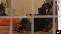 FILE - In this Saturday, Sept. 9, 2017 image made from video, a woman and a small child lie on the floor of a tent in a camp for displaced people on the outskirts of Mosul, Iraq. Over 1,300 women and children, all foreign nationals and relatives of Islamic Stat
