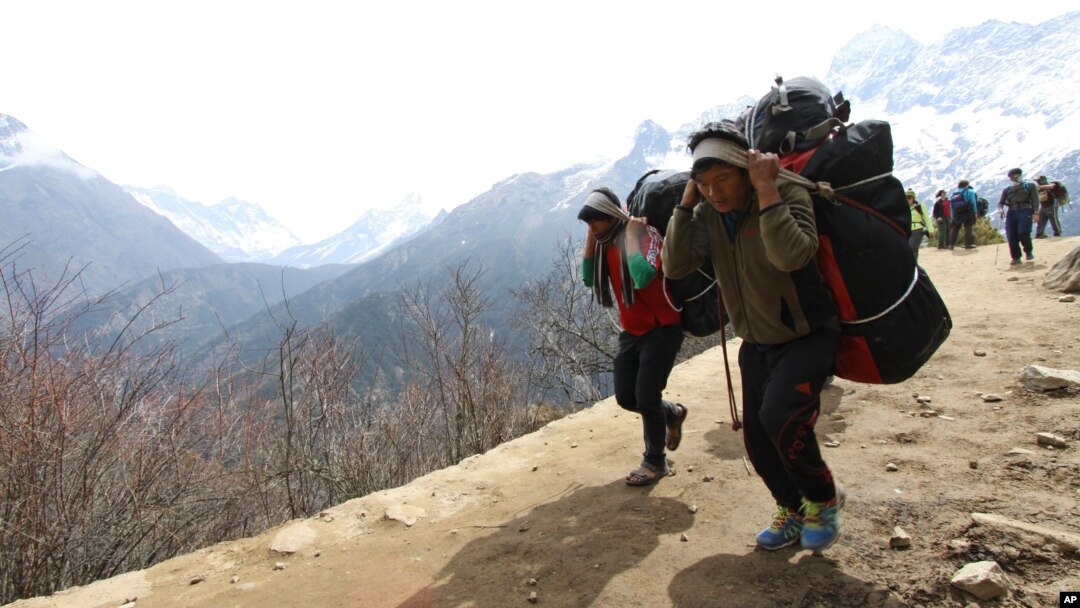FILE - Nepalese porters carry heavy loads for climbers on their way to Everest Base Camp at Kyangjuma, Nepal in this April 7, 2015 photo.. 