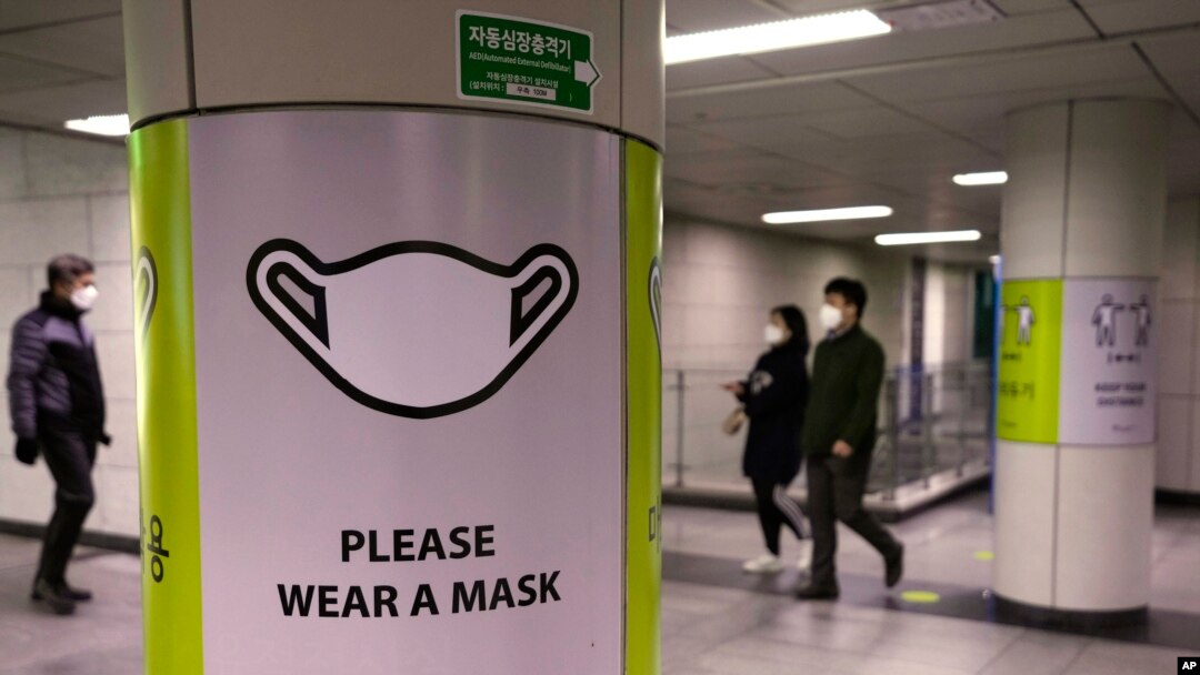 People wearing face masks pass by posters reminding precautions against the coronavirus at a subway station in Seoul, South Korea, Nov. 17, 2021. 