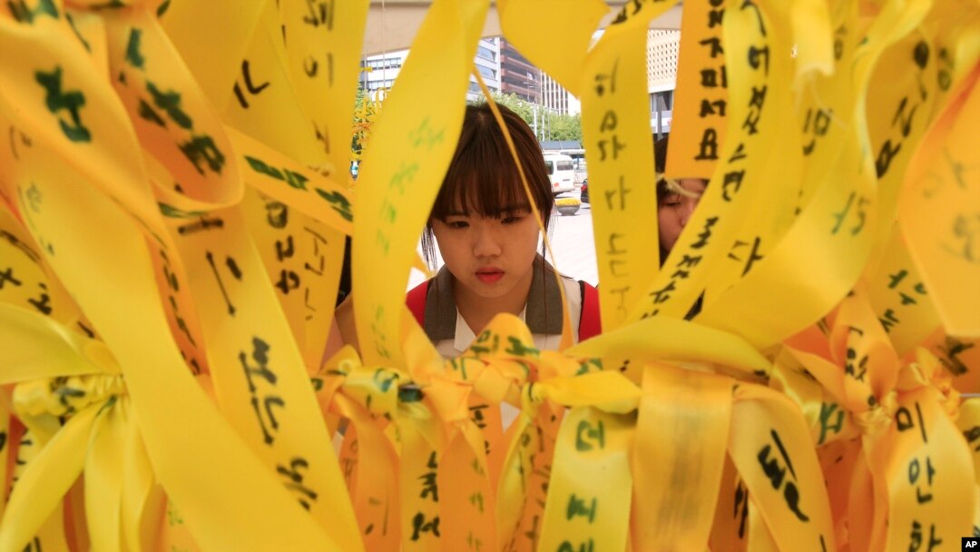 A high school student reads massages written on ribbons for the victims of the sunken ferry Sewol at a group memorial altar in Seoul, South Korea, May 15, 2014.
