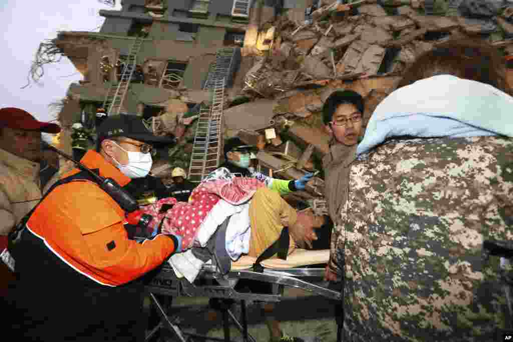 Rescue workers carry a man from the site of a toppled building.