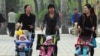 母亲们在公共假日推着婴儿车在北京某公园散步。（资料照）
