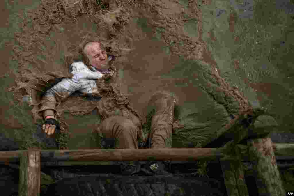 A competitor dressed in a white suit falls into muddy water in the Tough Guy endurance event near Wolverhampton, central England.