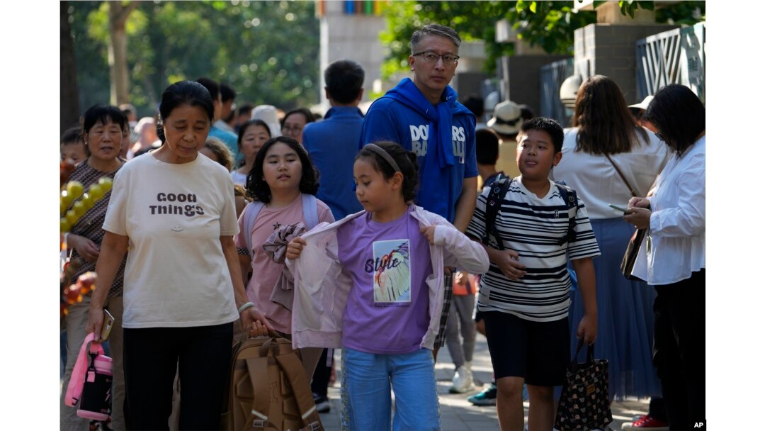 FILE - People pick up their children after school in Beijing, Friday, Sept. 13, 2024. (AP Photo/Andy Wong)