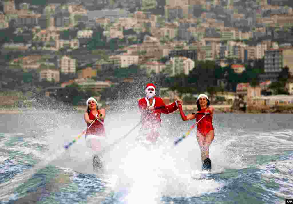 Members of a Lebanese water ski club perform while dressed in Santa Clause outfits in the bay of Jounieh.