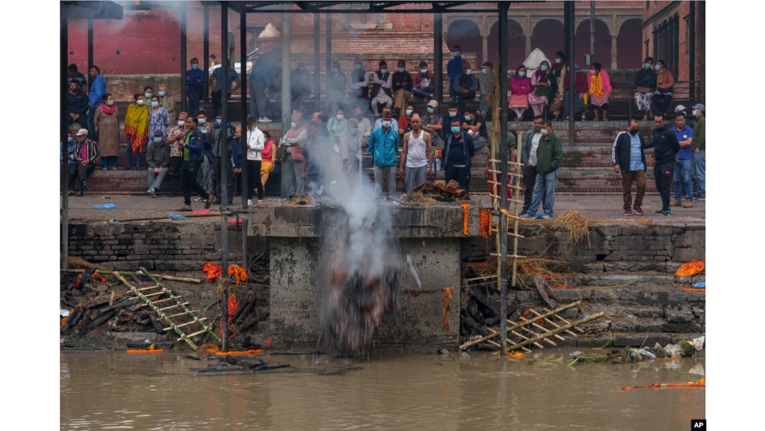 A man pushes cremated remains into the Bagmati River at the Pashupatinath Temple in Kathmandu, Nepal, Saturday, May 28, 2022. The temple was declared a World Heritage Site by UNESCO in 1979. (AP Photo/Niranjan Shrestha)