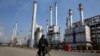 FILE - Iranian oil worker rides his bicycle at the Tehran's oil refinery south of the capital Tehran, Iran. Energy-poor Turkey relies on Iran's oil and is the largest importer of Iranian natural gas. 